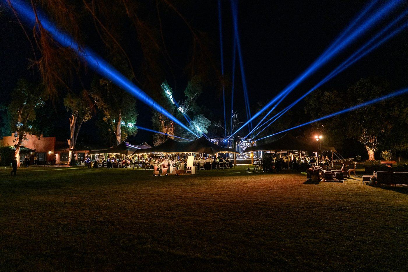 Parque de un evento iluminado de noche con haces de luz, el parque como escenario
