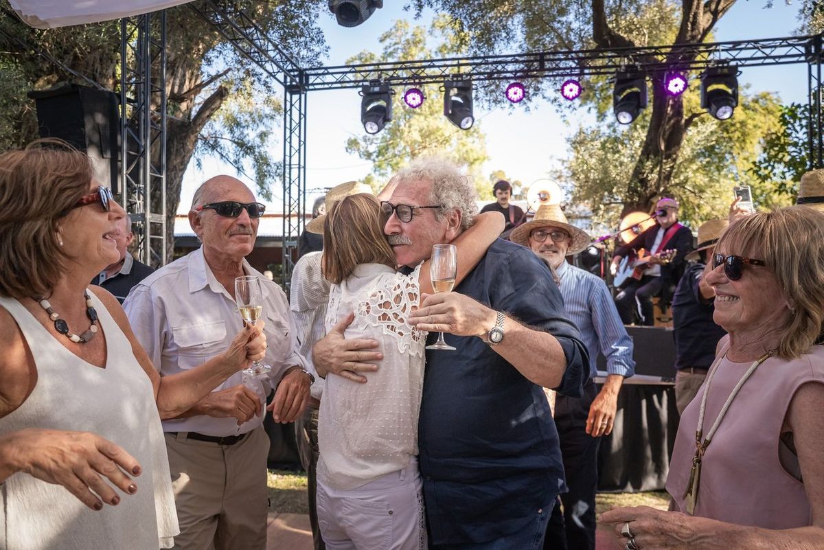 Jorge, el homenajeado, abraz&aacute;ndose con una invitada y brindando con la banda tocando de fondo