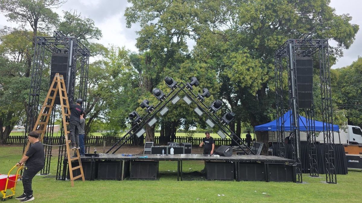 Escenario armado al aire libre con dos torres de line array e iluminaci&oacute;n en arco