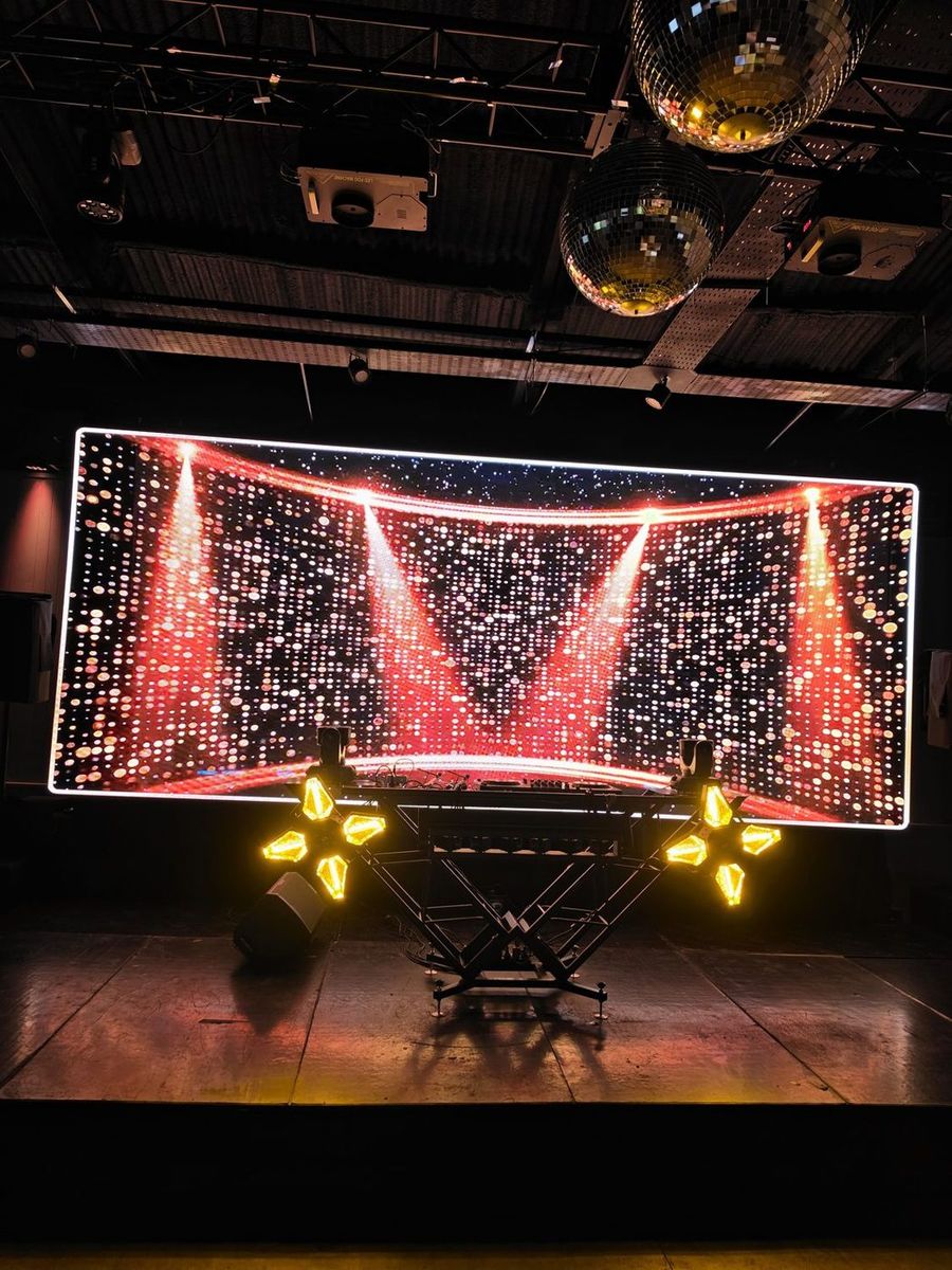 Cabina de DJ con pantalla LED y esferas espejadas en la fiesta de una boda