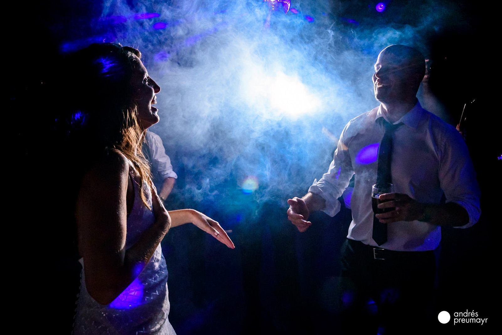 Los novios bailando entre humo y contraluz azul en la pista, con iluminaci&oacute;n de GS T&eacute;cnica