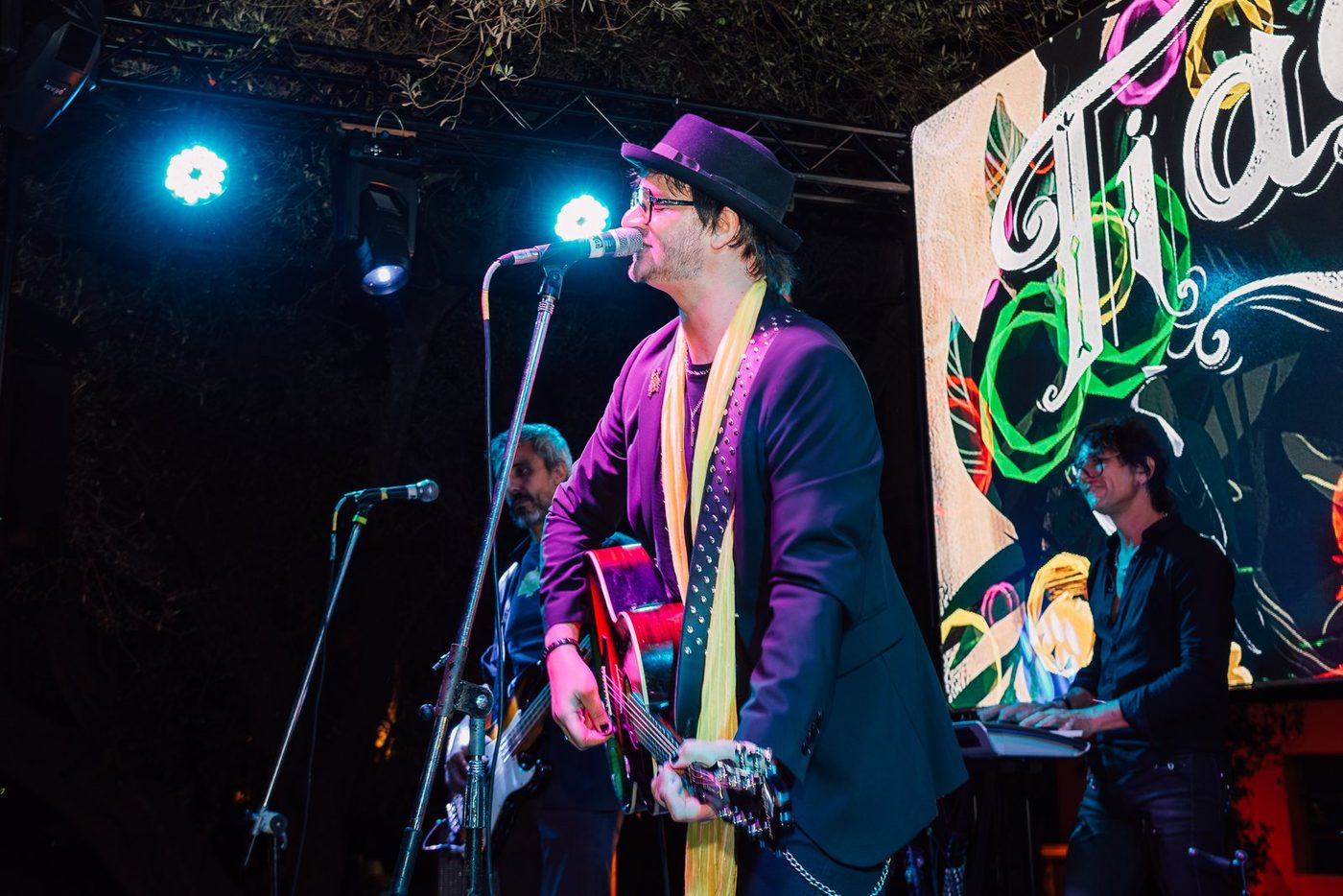 Cantante con guitarra en el escenario de noche con la pantalla LED encendida
