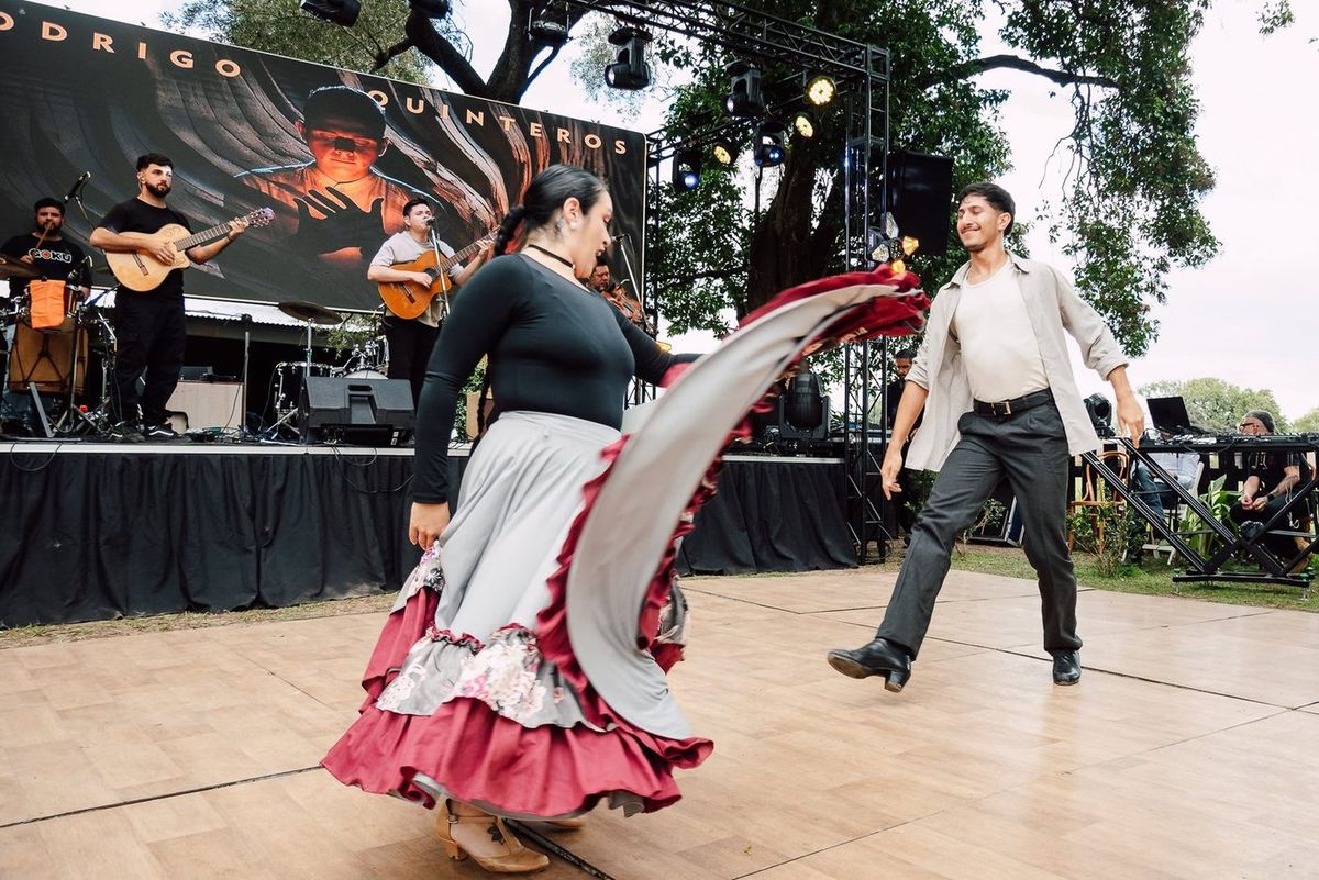 Pareja de baile folkl&oacute;rico en la pista con la banda de folklore tocando en vivo detr&aacute;s