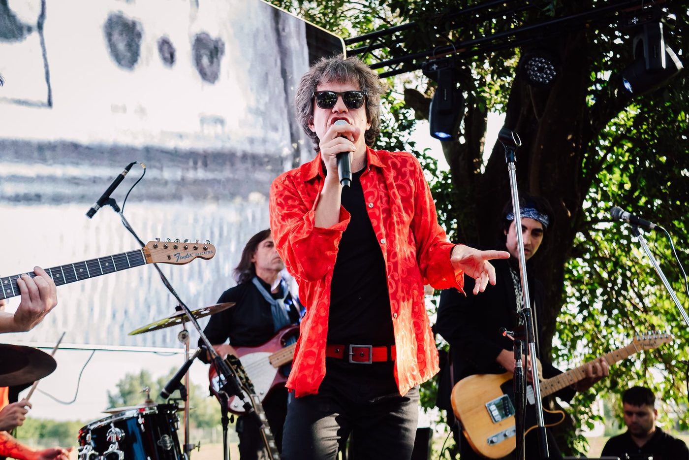 Cantante de una banda de rock con saco rojo en el escenario, de d&iacute;a