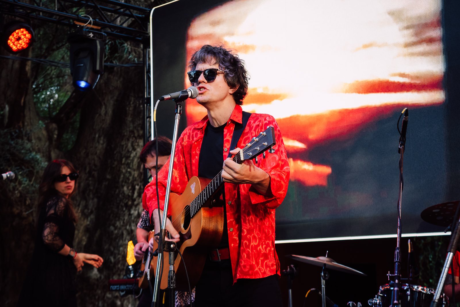 Cantante iluminado con luz roja escénica al caer la tarde