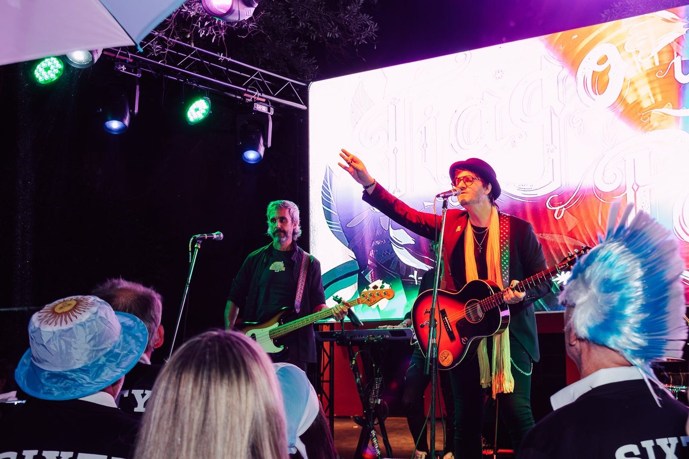 Banda de rock de noche con iluminaci&oacute;n de colores y el p&uacute;blico de fondo
