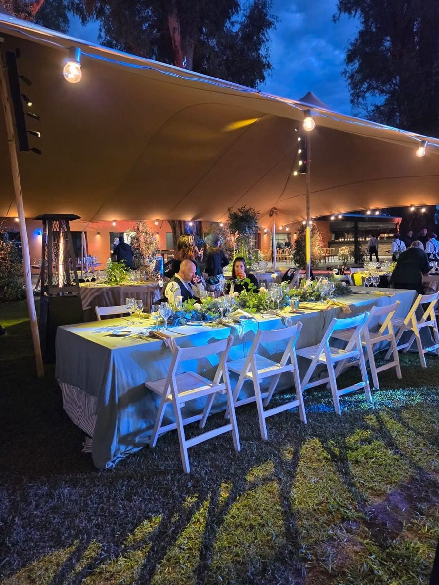Mesas de cena iluminadas bajo carpas beduinas con guirnaldas de luz