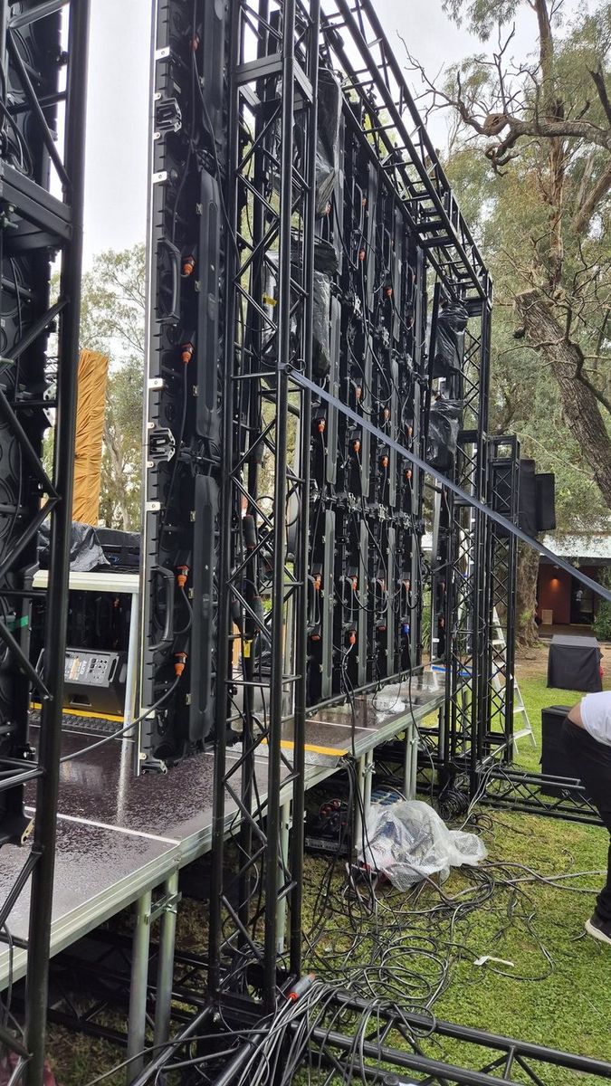 Montaje de la pantalla LED modular sobre estructura de truss, con el piso mojado por la lluvia