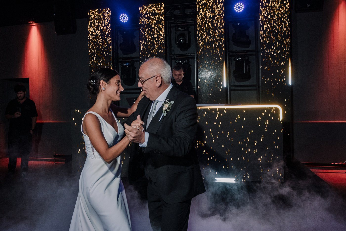 Los novios en el primer baile con humo bajo e iluminación escénica